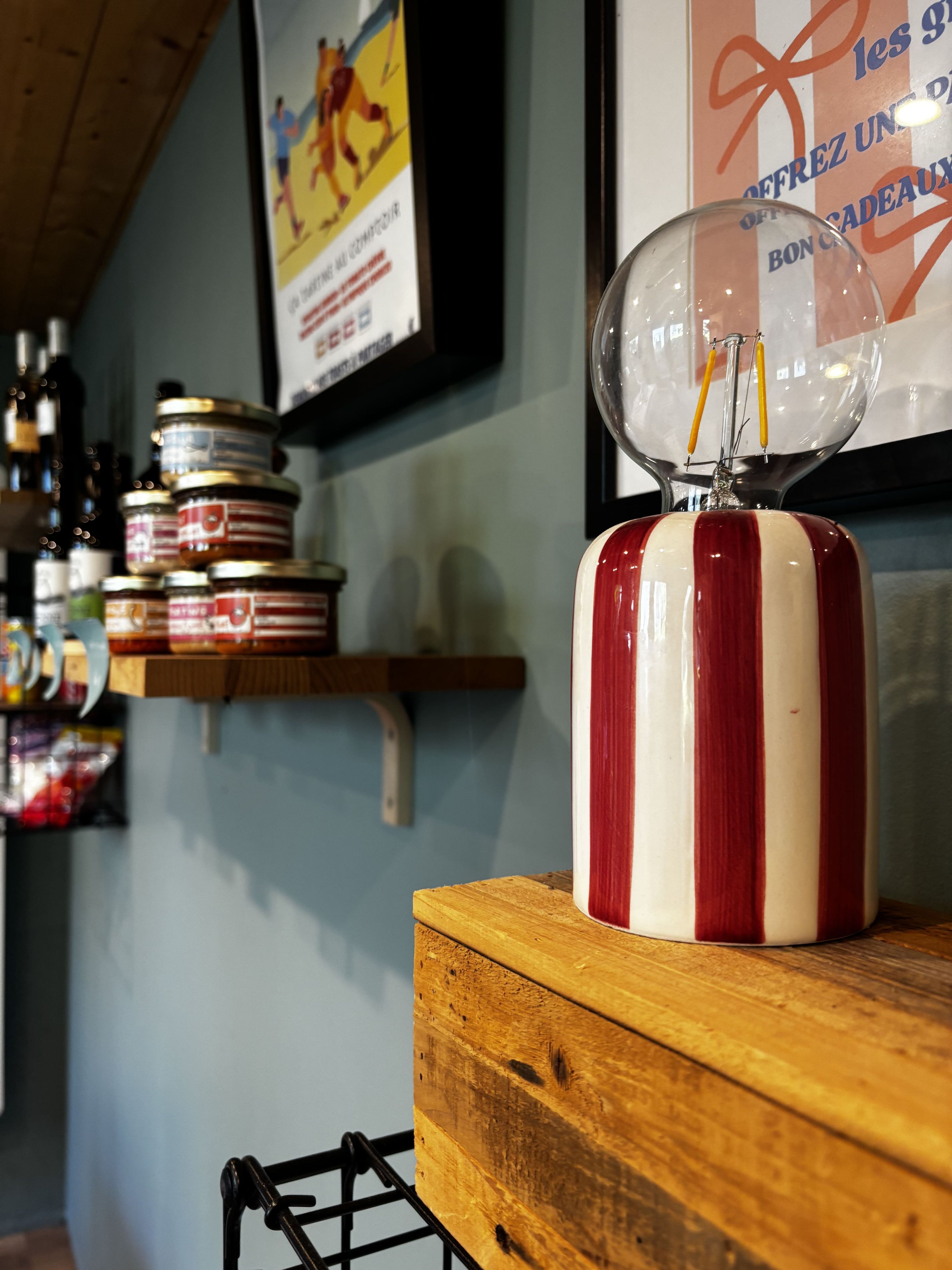 A kitchen counter with a red and white striped container, a glass dome with a thermometer, and shelves with jars and bottles.