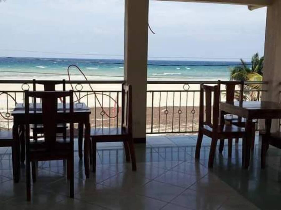 Un espacio de descanso al aire libre cubierto con mesas y sillas, con vistas a una playa y al océano.