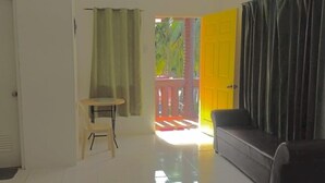 Une pièce avec une porte donnant sur un espace extérieur, une petite table avec une chaise et un canapé.