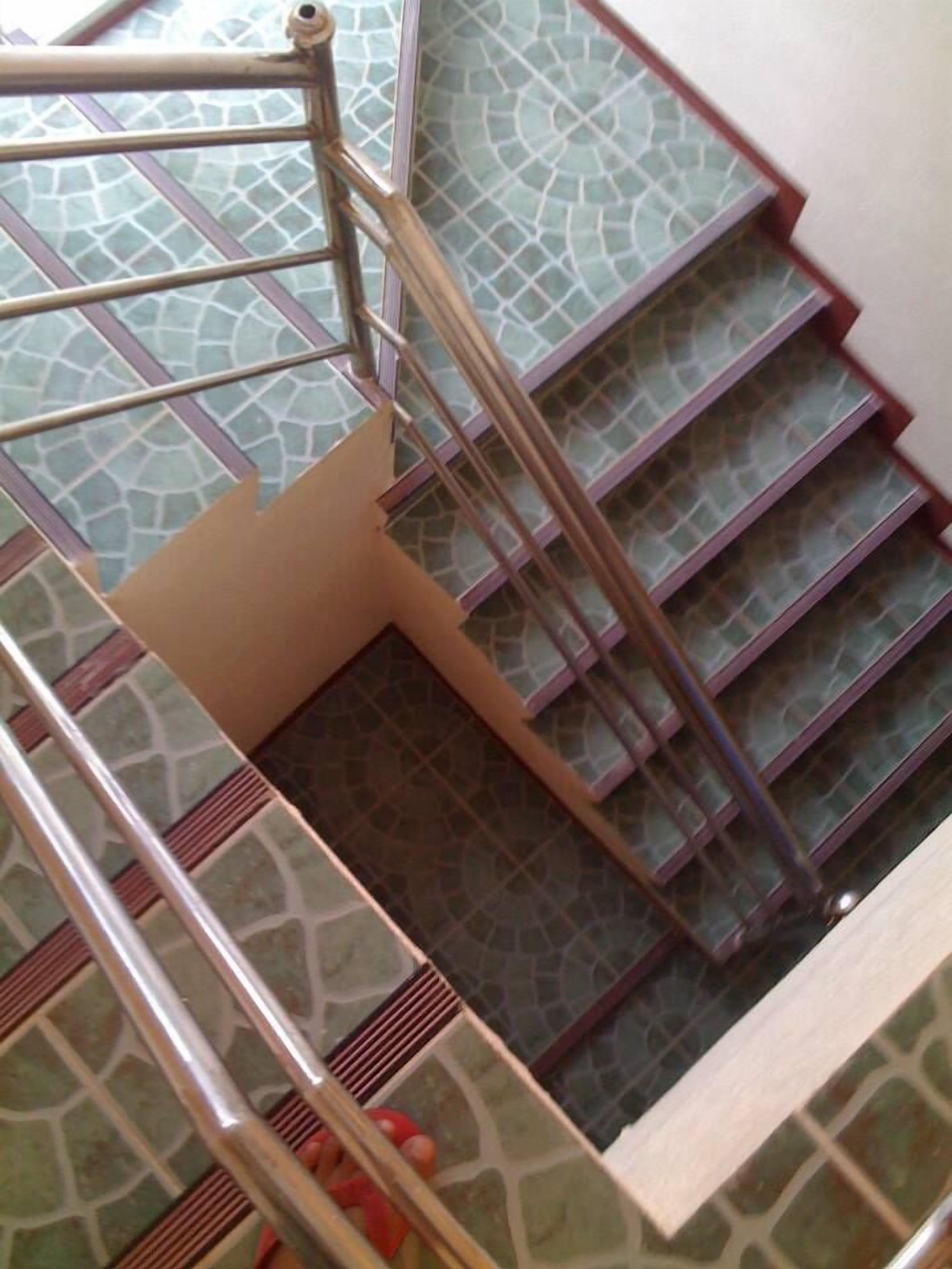 Una escalera de caracol con suelo estampado y barandillas metálicas.