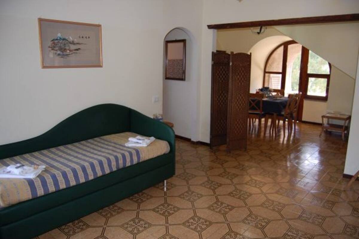 Ein Zimmer mit einem grünen Sofa, einem Fliesenboden, einem Essbereich mit Tisch und Stühlen sowie einem Fenster mit Blick.