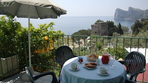 A table with breakfast items and a view of the sea.