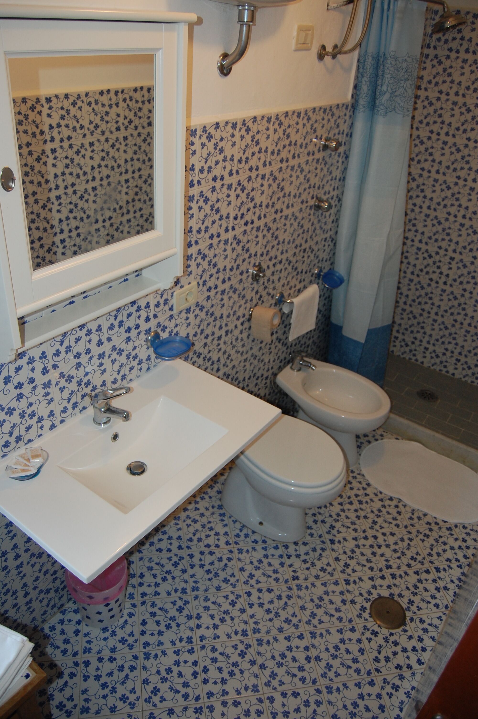 A bathroom with a white sink, two toilets, and a shower area.