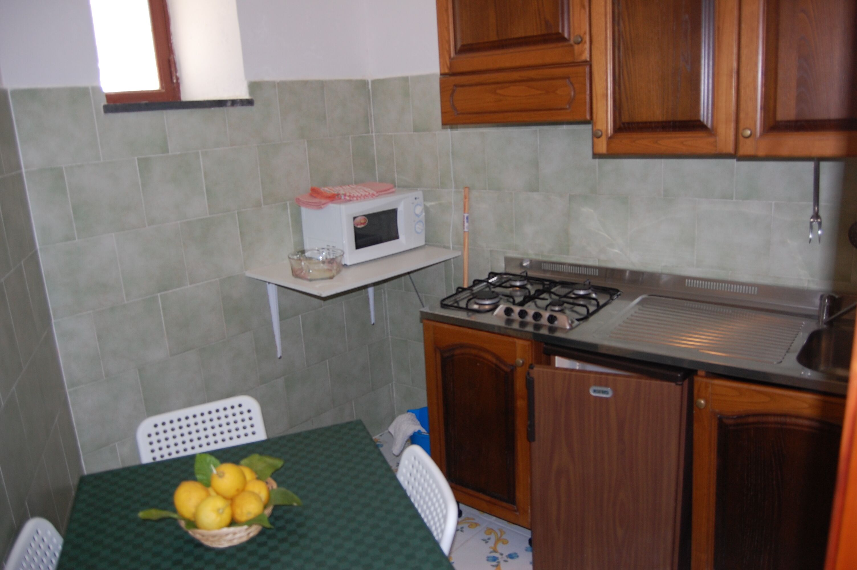 Una cocina pequeña con microondas, estufa y una mesa con una cesta de limones.