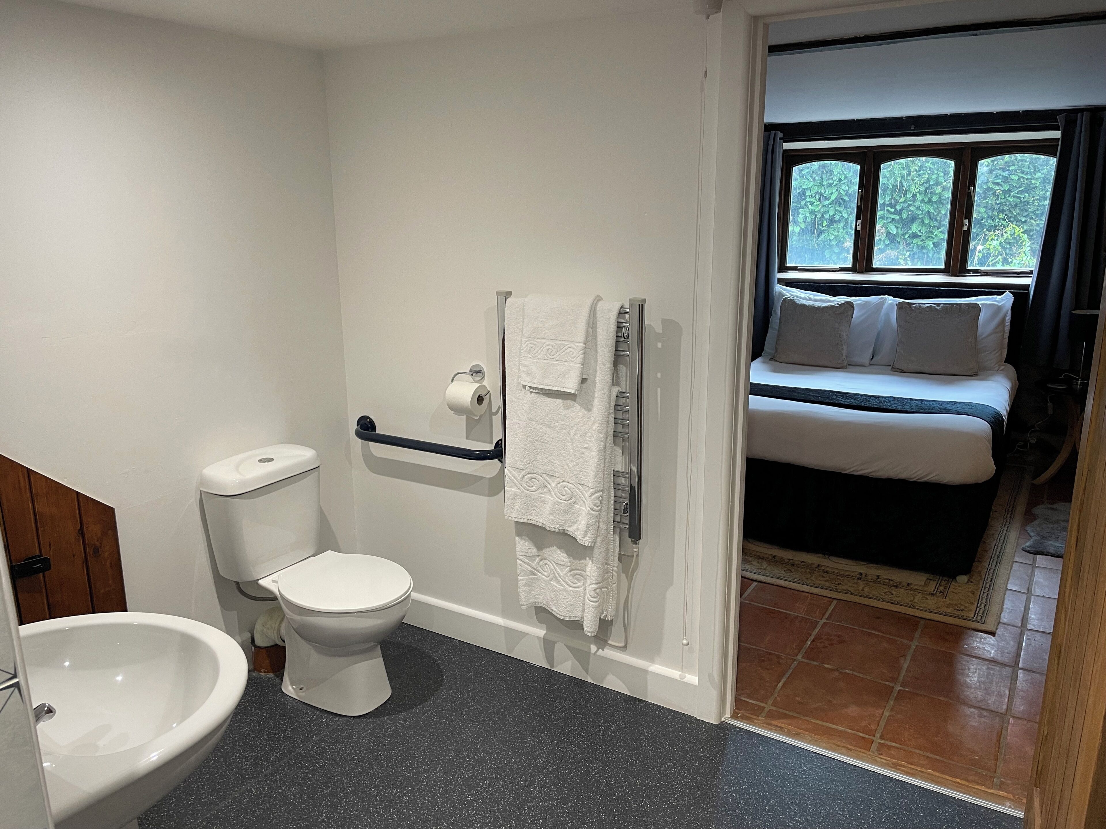 A bathroom with a toilet, bidet, and towel rack.