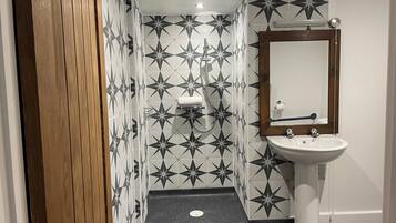 A bathroom with a star-patterned tile wall, a white pedestal sink, and a wooden door.