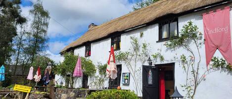 A traditional white building with a thatched roof, ivy, and a sign for The Criford Inn.
