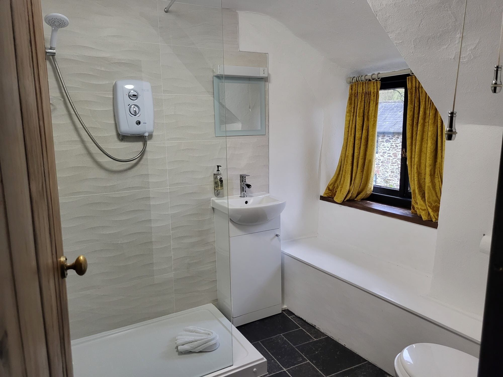 Een badkamer met een douche, wastafel en toilet.