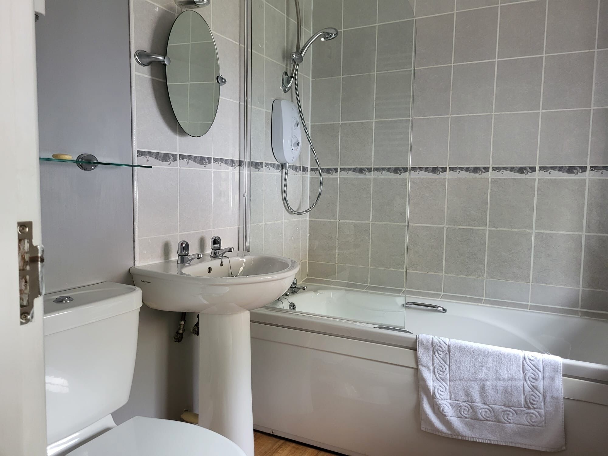 A bathroom with a toilet, sink, mirror, and bathtub.