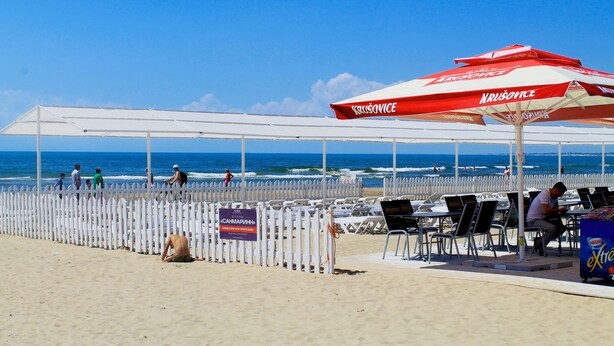 A beachside restaurant with outdoor seating, a white fence, and a view of the ocean. - SunMarInn Resort (Anapa)