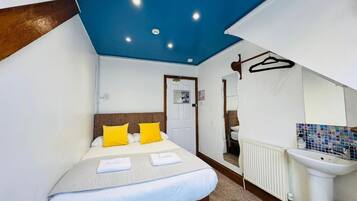 Una habitación de hotel con una cama, un radiador blanco, un lavamanos y un espejo.