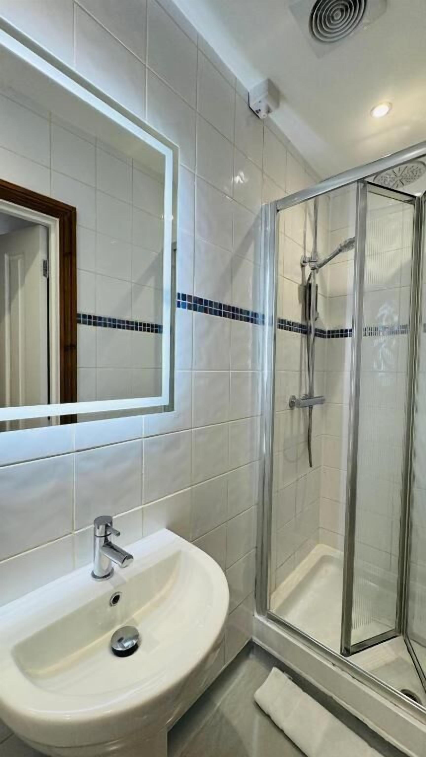 Un baño con lavamanos, espejo y ducha.