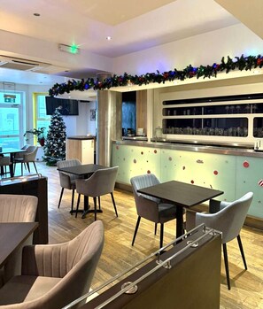 A modern restaurant with a bar area, wooden flooring, and a Christmas tree. - Town Lodge (Newquay)