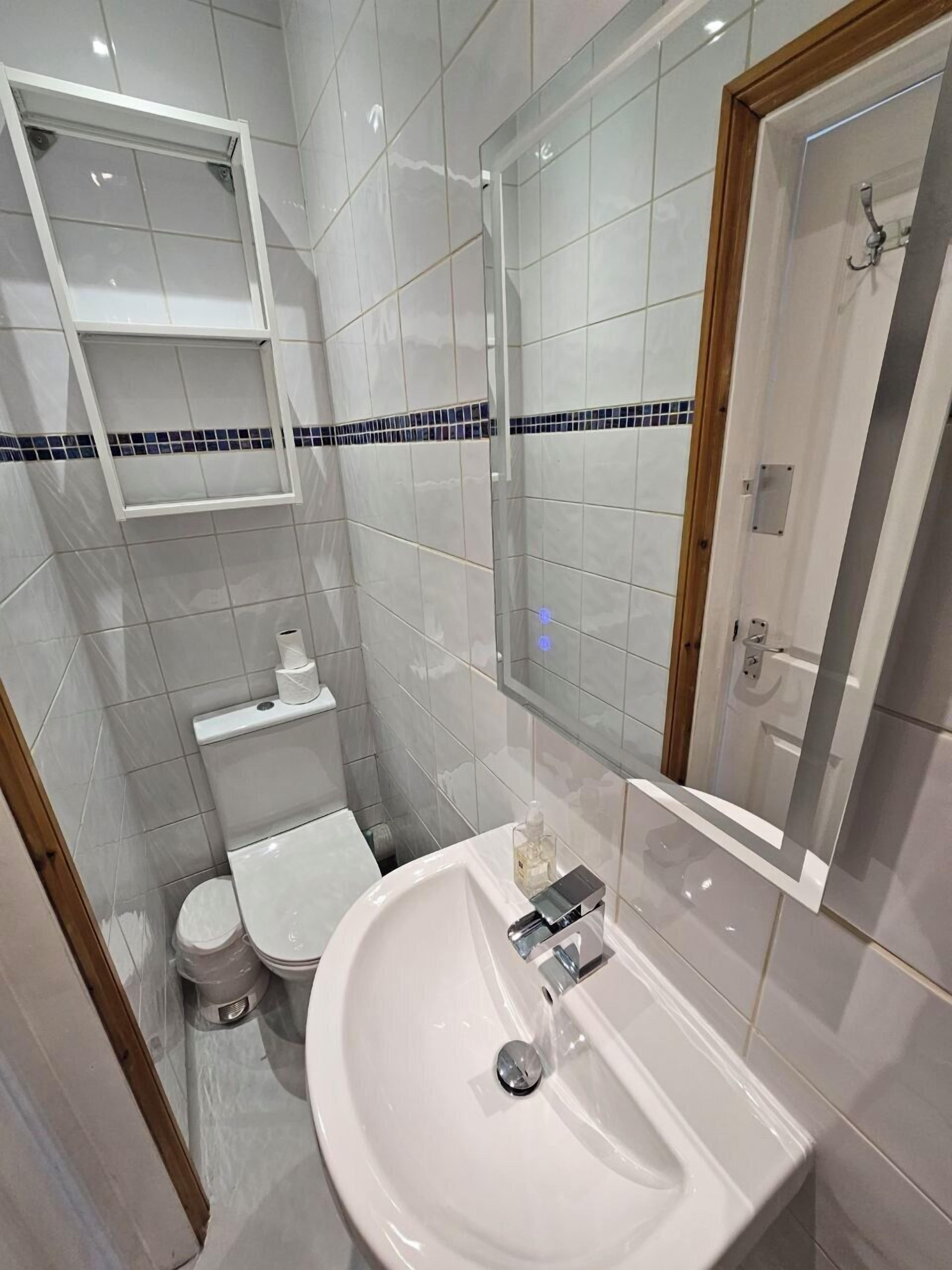 A compact bathroom with a white sink, a toilet, and a shower area.