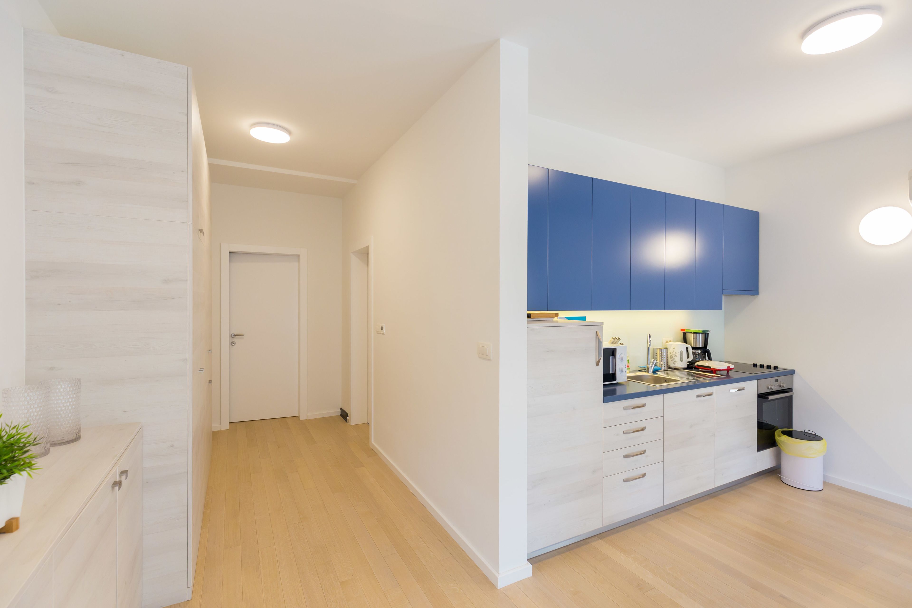 Una cocina moderna con armarios blancos, un mueble superior azul y encimera de madera.