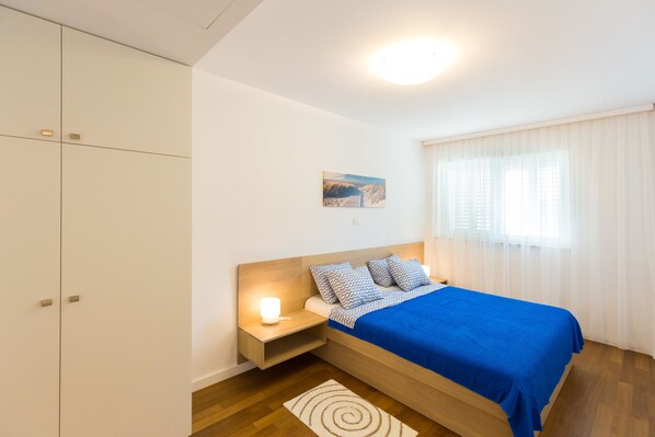 A bedroom with a bed, nightstand, and wardrobe. - Antonio Luxury Beach Suites (Dubrovnik)
