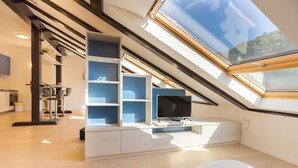 Une chambre de style loft moderne, dotée d’une lucarne, d’étagères intégrées, d’un téléviseur à écran plat et d’un design minimaliste.