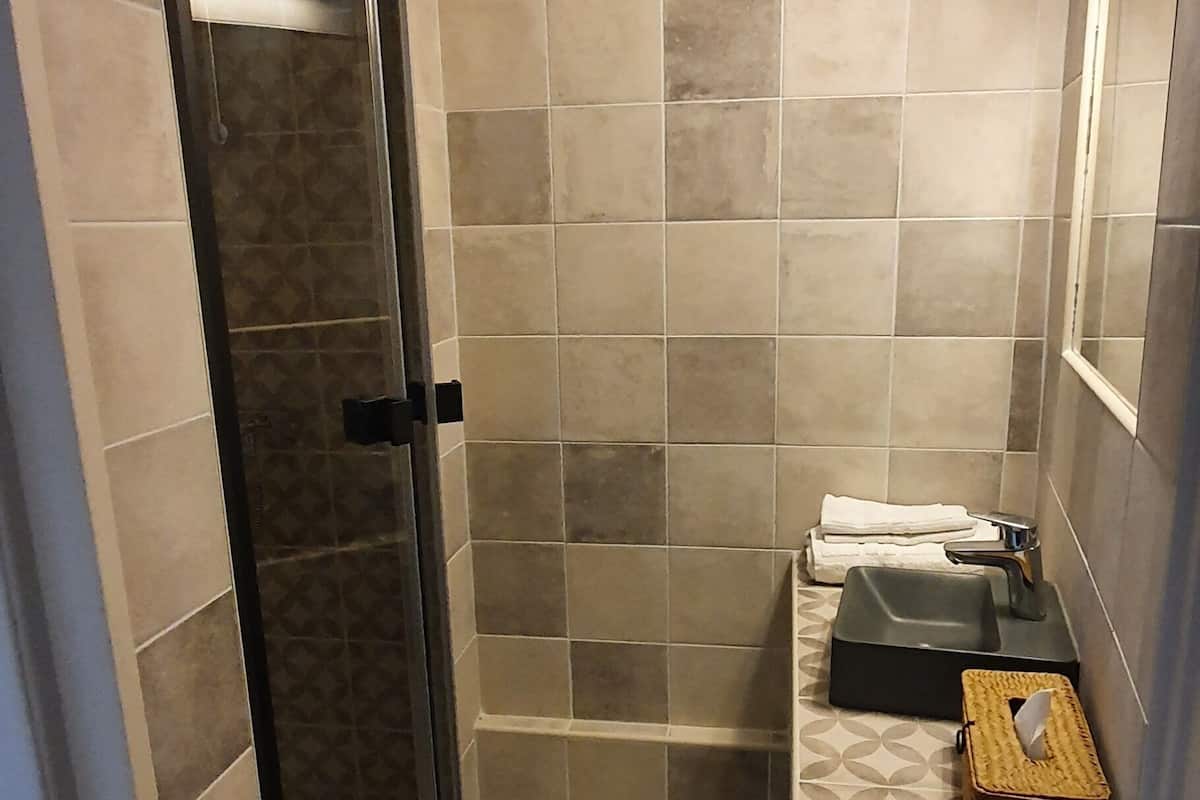 A bathroom with a glass shower door, a sink with a mirror, and a towel rack.