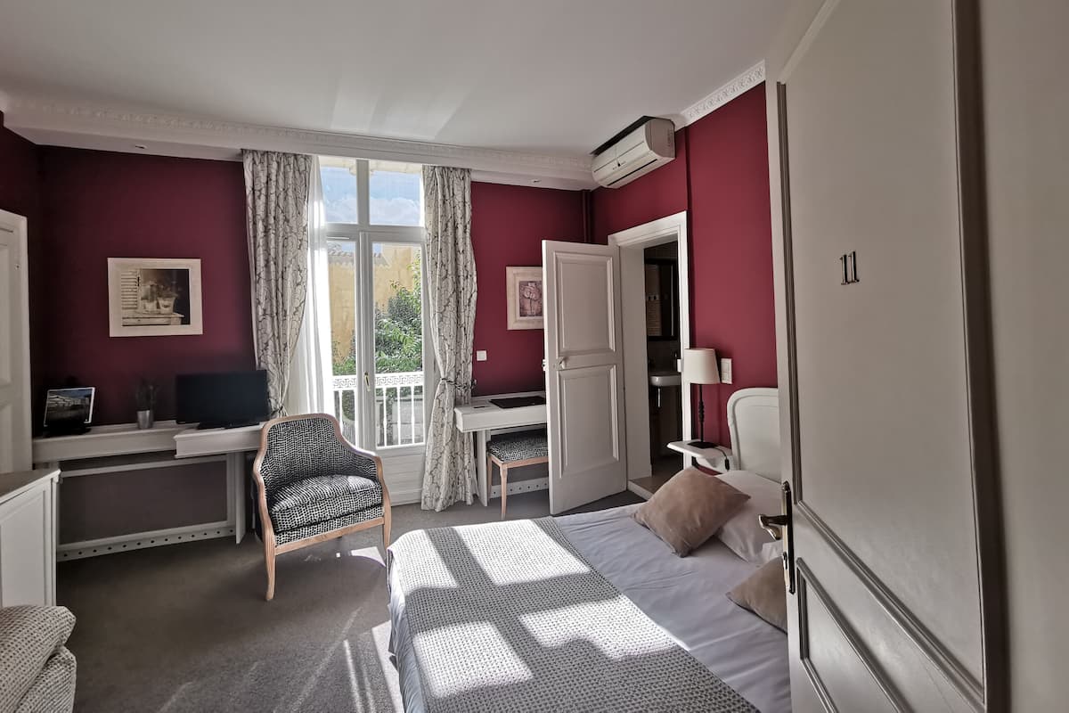 A hotel room with a bed, a desk, a chair, a TV, and a bathroom.