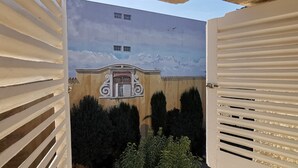 A view through a gate with a building featuring a mural of clouds and a decorative entrance. - Hotel du Parc - Montpellier (Montpellier)