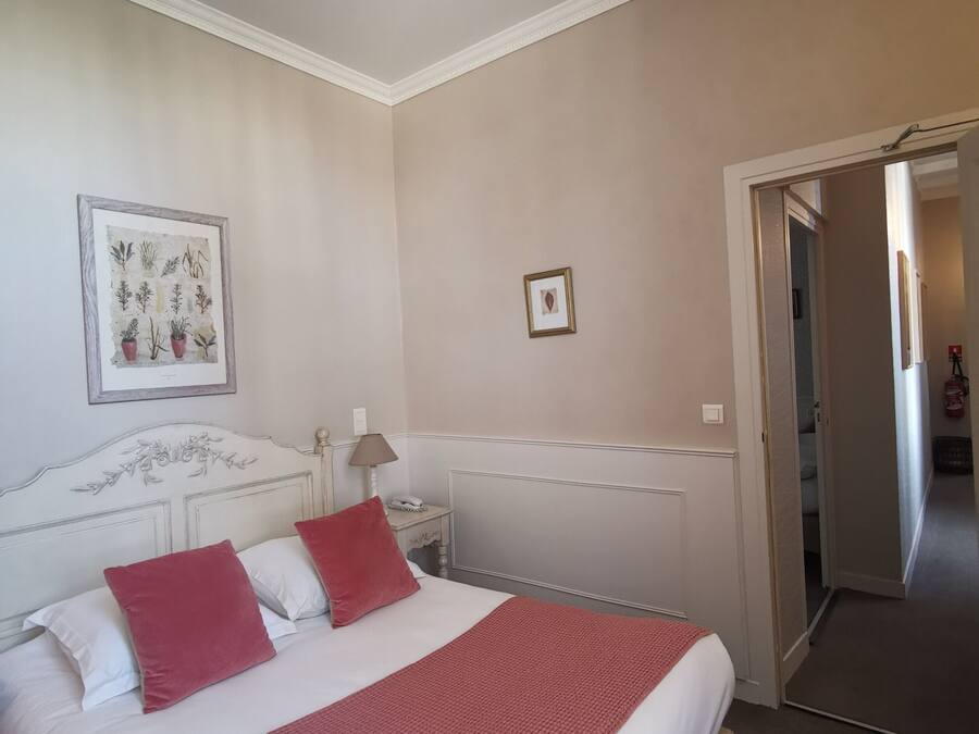 Una camera da letto con un letto, un comodino, una lampada, un'illustrazione botanica incorniciata e un termosifone.
