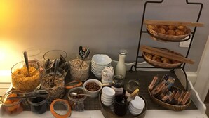 A breakfast buffet with various food items and utensils, including jars of cereal, nuts, and spreads, arranged on a table. - Hotel du Parc - Montpellier (Montpellier)