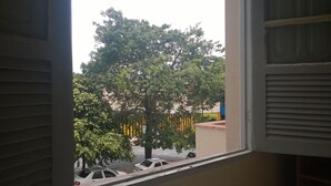 Blick aus einem Fenster mit Baum und parkenden Autos vor der Tür.