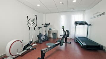 A fitness room with cardio equipment including a treadmill, stationary bike, elliptical, and rowing machine.