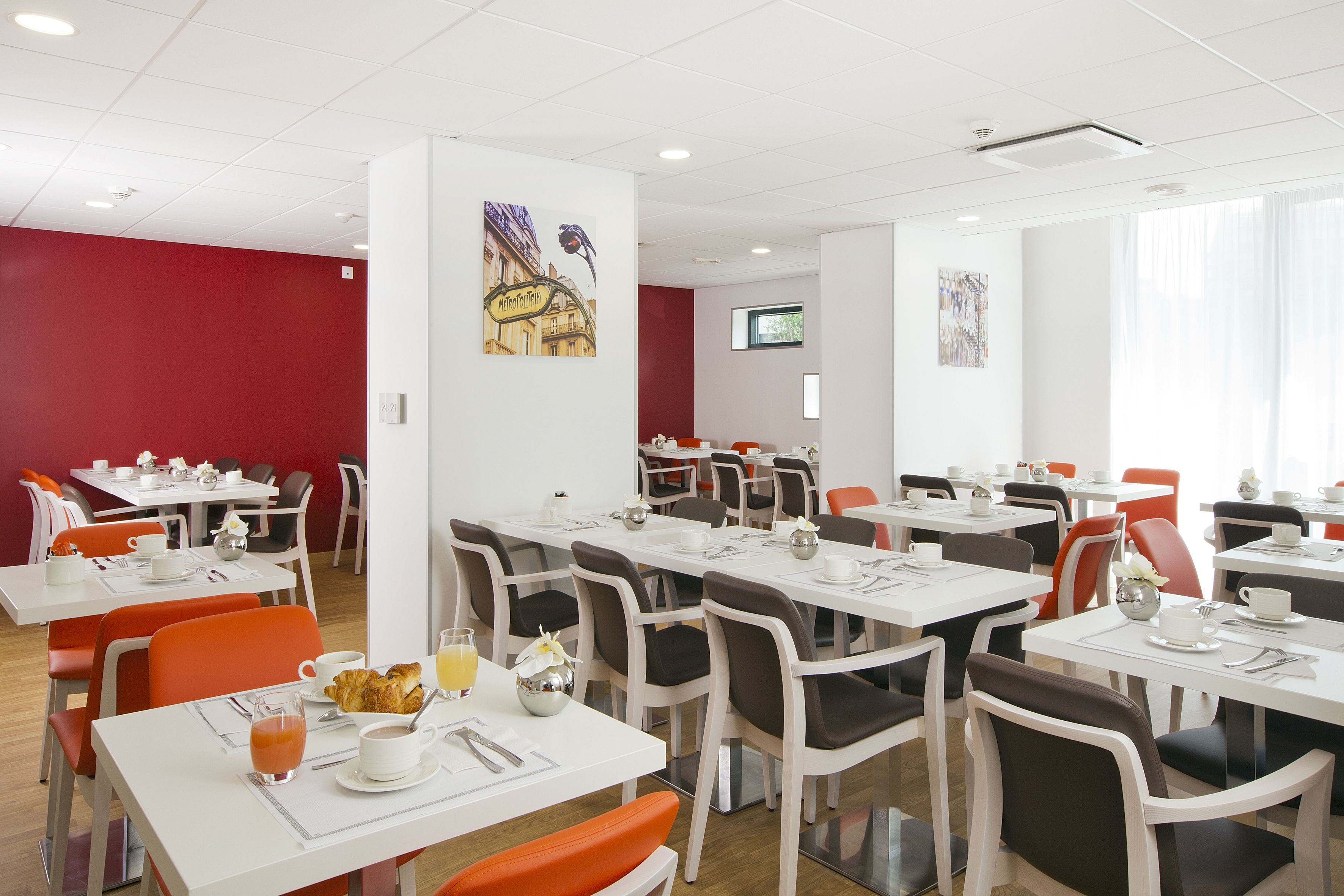 A spacious dining area with multiple tables and chairs, equipped with dining essentials like cups, plates, and cutlery.