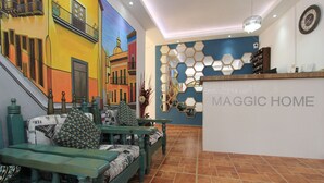 Uma área de recepção com design moderno, incluindo um balcão de atendimento, um mural e uma parede com espelhos hexagonais.