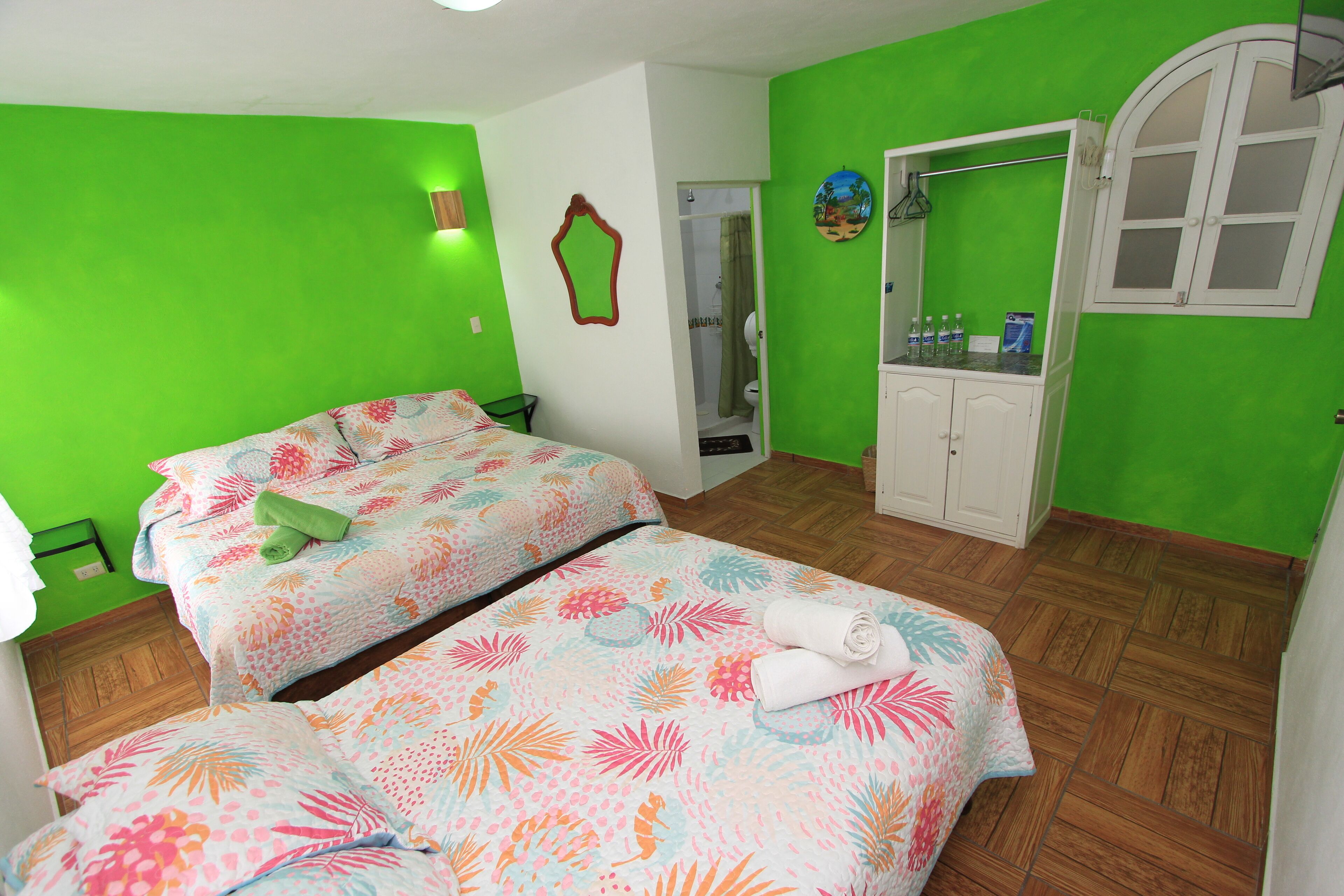 Een kamer met twee bedden, een badkamer en een klein kitchenette.