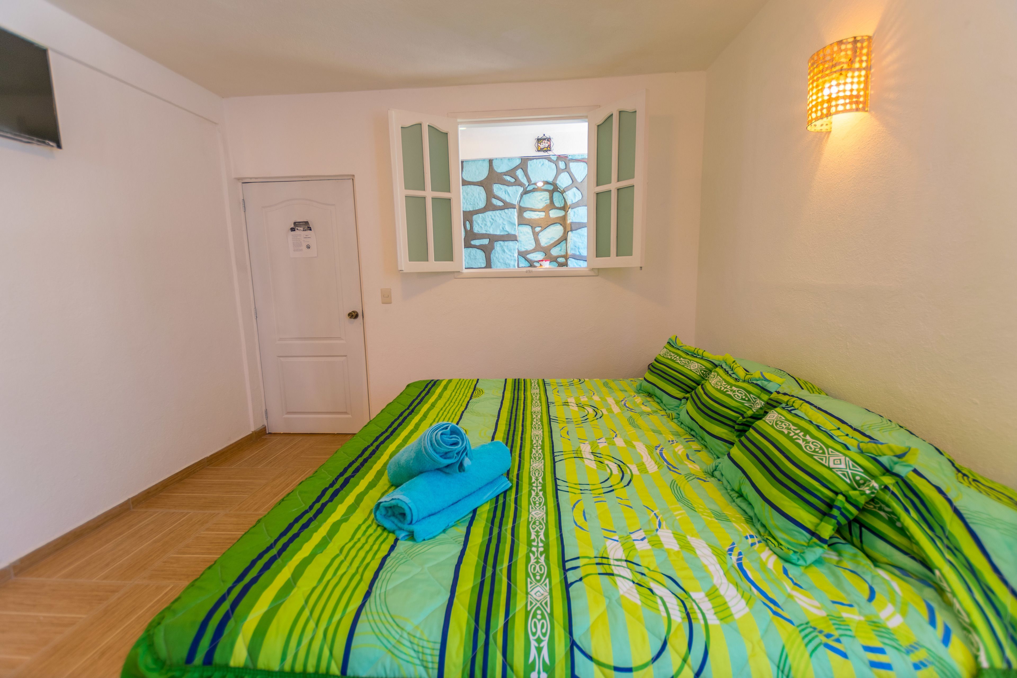 Un dormitorio con cama, ventana con vistas y puerta.