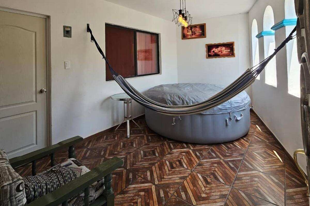 A room with a hammock, a bean bag, a small table, and a patterned floor.