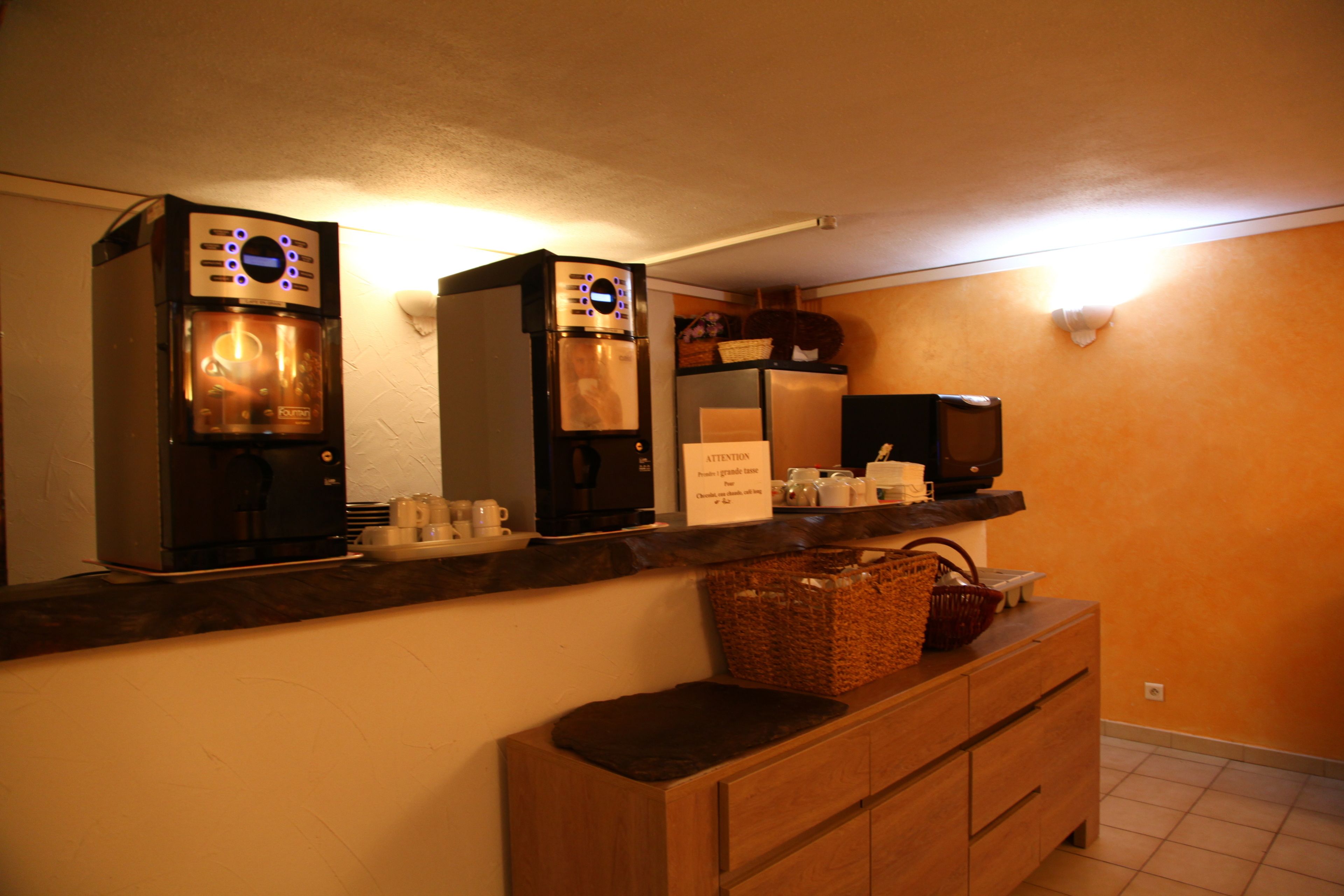 Una kitchenette con cafetera, microondas y tostadora. Hay un mueble de madera debajo de la encimera.
