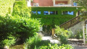 Un patio con una escalera de piedra, abundante vegetación y edificios con muros cubiertos de hiedra.