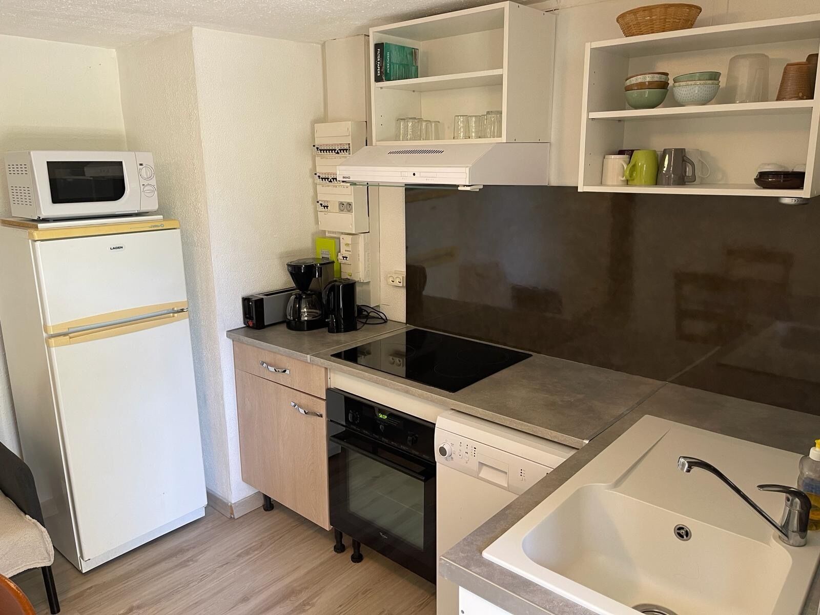 Cocina compacta con microondas, cafetera, lavavajillas y fregadero.