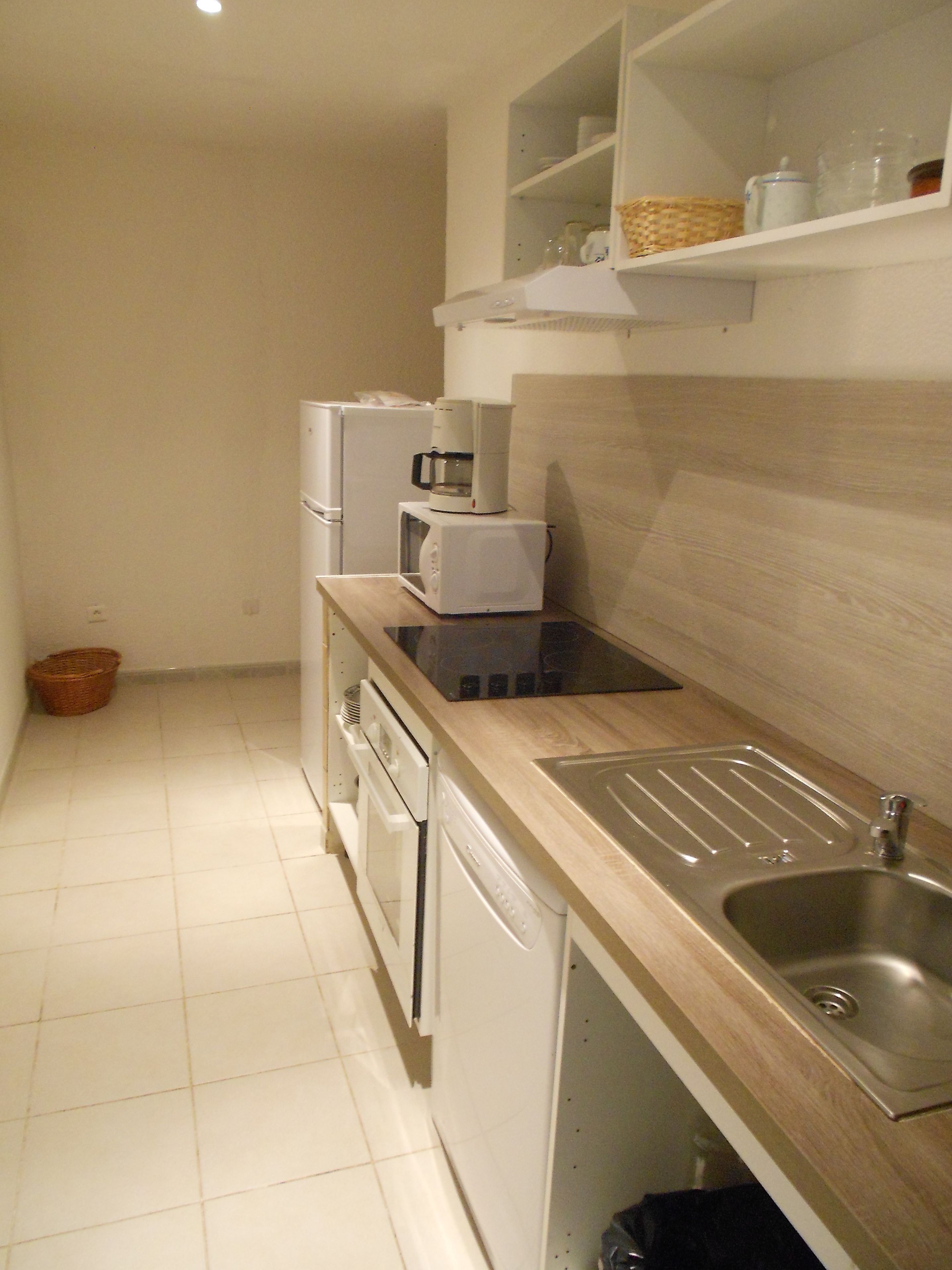 A compact kitchen with a microwave, coffee maker, and a sink.