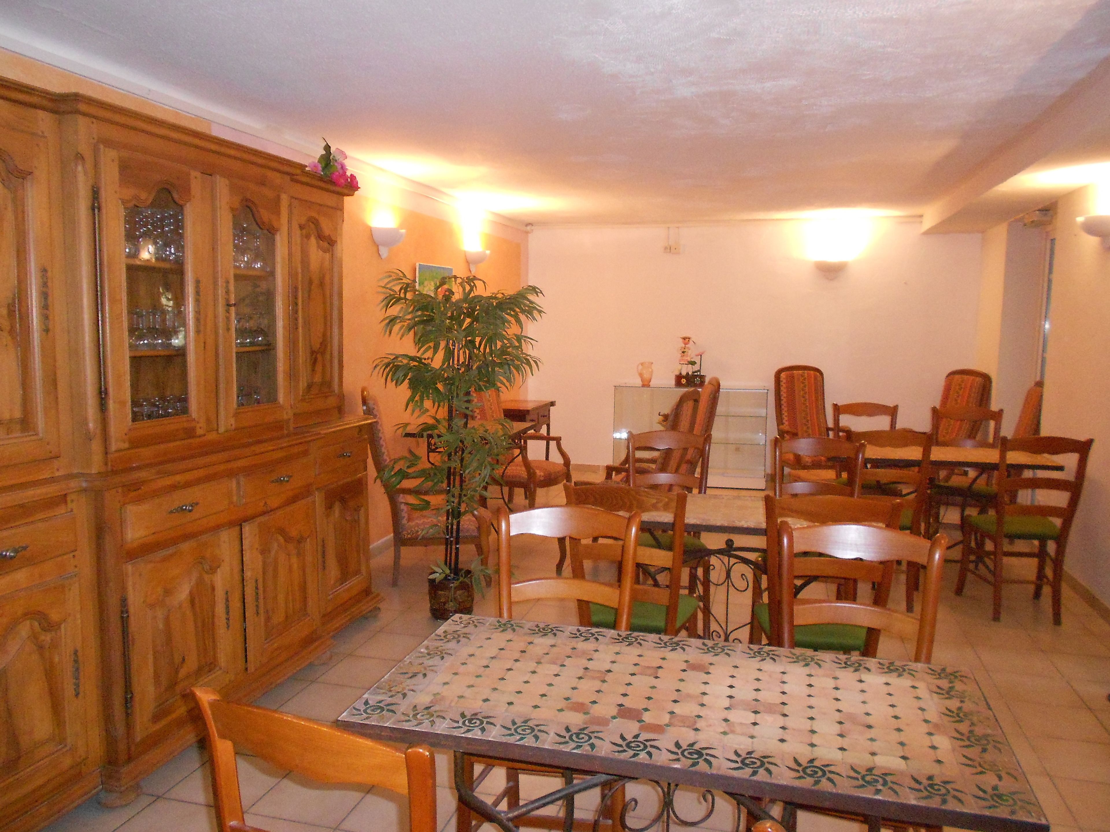 Un comedor con un armario de madera, una mesa con mantel estampado y varias sillas.