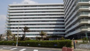 Un hotel de varios pisos con un diseño moderno, con balcones en cada planta y una vista despejada del entorno.