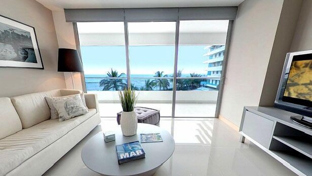 Una sala de estar moderna con sofá, mesa de centro y mueble para televisión.