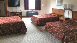 Une chambre d’hôtel avec deux lits, un bureau, une chaise, une télévision et un radiateur.