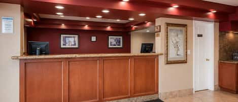 A reception desk with a clock, framed pictures, and a door to the right.