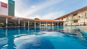 Un hotel con piscina, mobiliario exterior y cielo despejado.