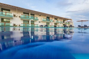 Ett hotell med en swimmingpool, flera balkonger och utomhusområden med sittplatser.