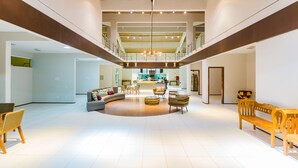 Un hall amplio con una zona de estar central, una escalera y una cocina al fondo.