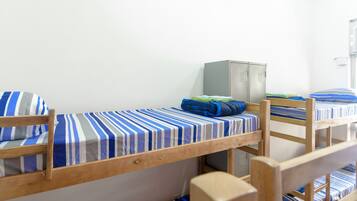 A dormitory room with bunk beds, a wardrobe, and a desk.