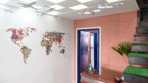 A room with a world map mural, a staircase with green artificial grass, and a door with a blue frame.