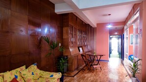 A cozy living area with a wooden sofa, a dining table with chairs, and a kitchen area with cabinets and a refrigerator.