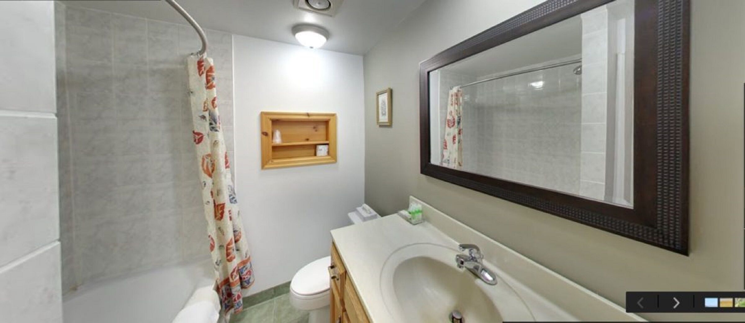 A bathroom with a shower, toilet, sink, and a mirror.