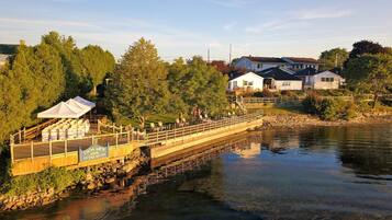Una passeggiata lungo il fiume con un ponte di legno, una tenda bianca e un cartello per Dewar's Inn.